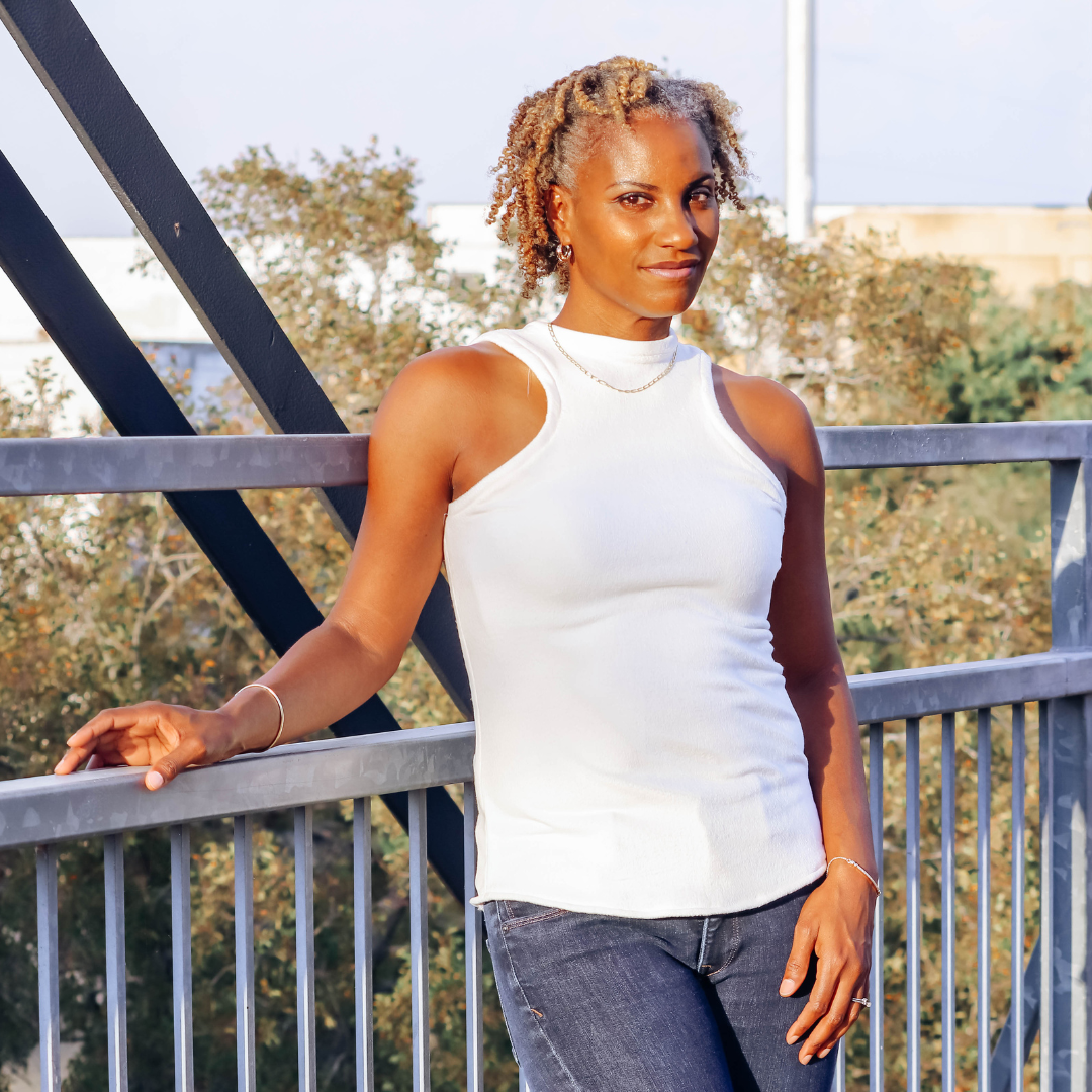 beautiful black woman in white sleeveless top and blue jeans on a bridge on a bright sunny day